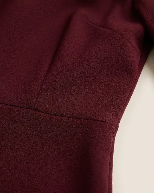 Close-up of the matte crepe fabric and waist seam of the Burgundy Midi Dress